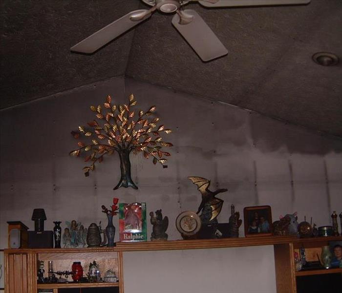 A fire mantle with many decorations, but behind the wall is covered in black smoke damage.