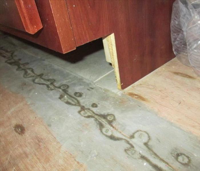 Beneath a drawer in a bathroom where water damage caused the removal of the tiles.
