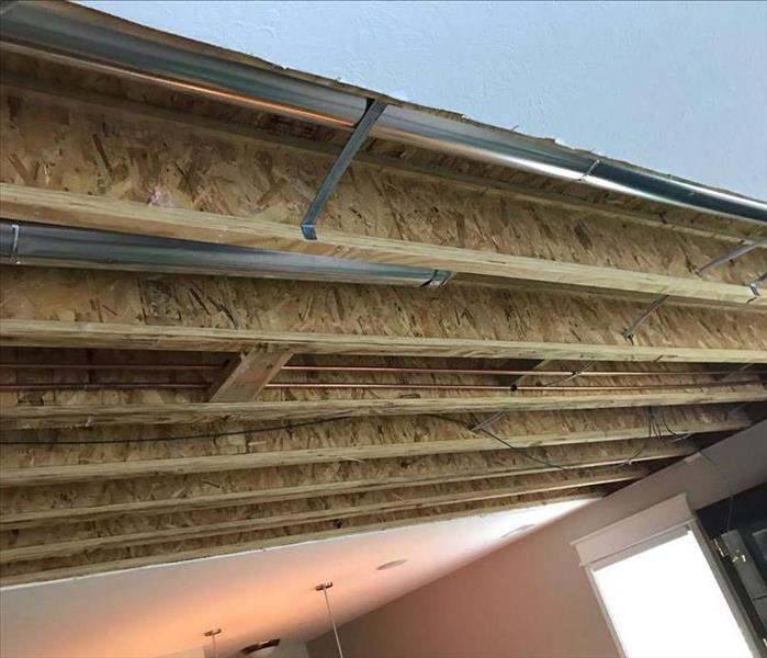 The ceiling of a home without panels, exposing the interior structure due to a water damage issue.