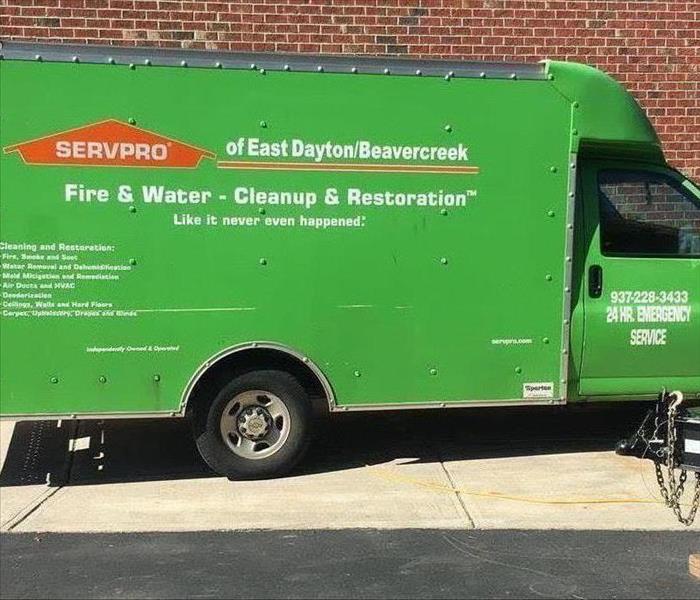A SERVPRO of Beavercreek and East Dayton green truck parked by a building.