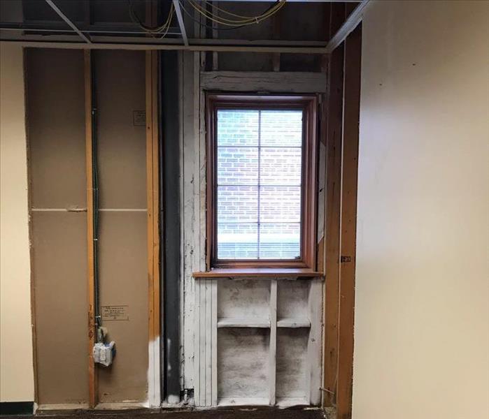 The drywall in an office has been removed, showing the interior wood beams.