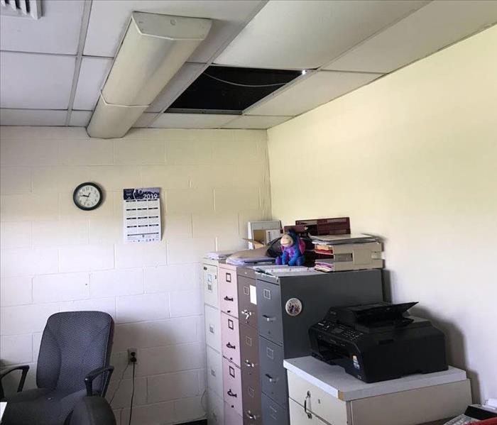 A ceiling of a school's office with missing ceiling tiles due to water damage.