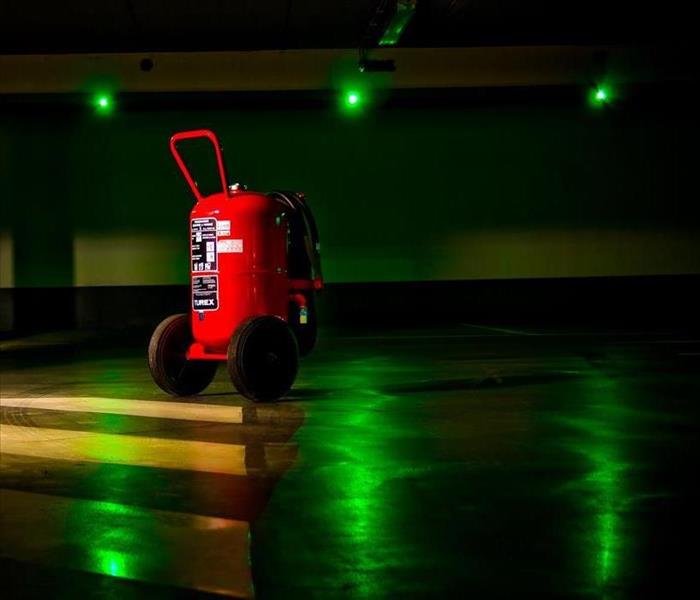 A fire extinguisher in the middle of an empty parking garage.